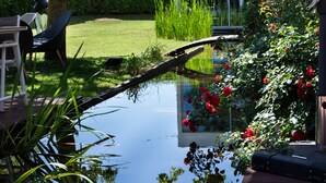 A garden with a pond, chairs, and a statue.