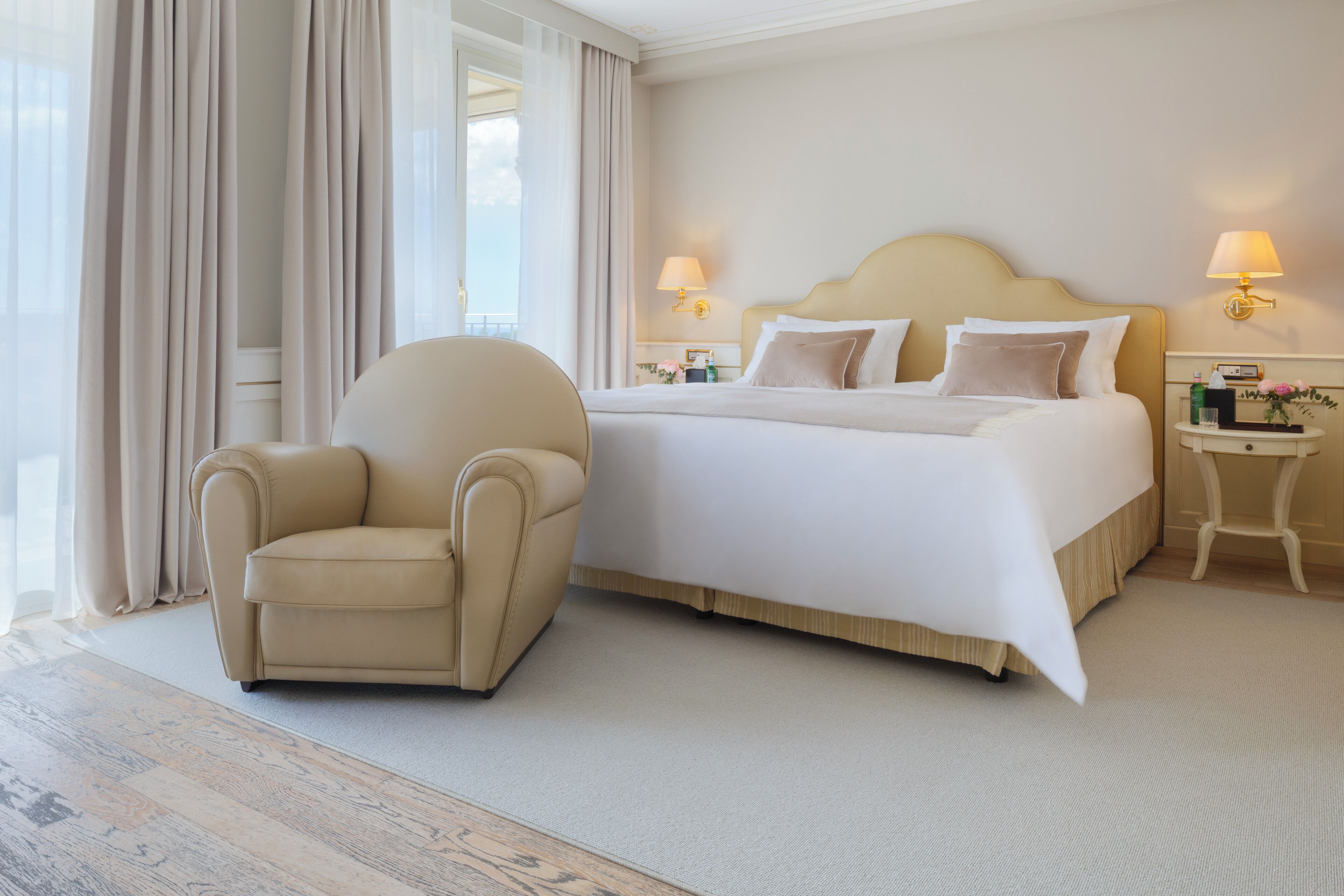 A hotel room with a large bed, a chair, and two bedside tables with lamps.