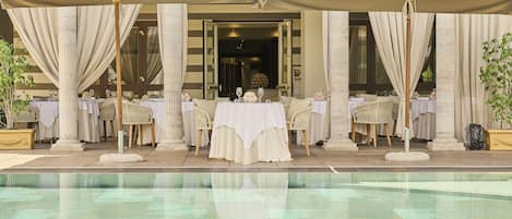 Una piscina techada, una piscina al aire libre, sombrillas