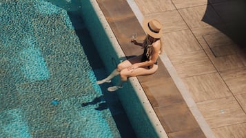 Area piscina con una poltrona da relax e una persona seduta a bordo vasca.