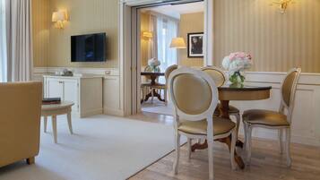 A hotel room with a dining area, a television, and a view of the hallway.