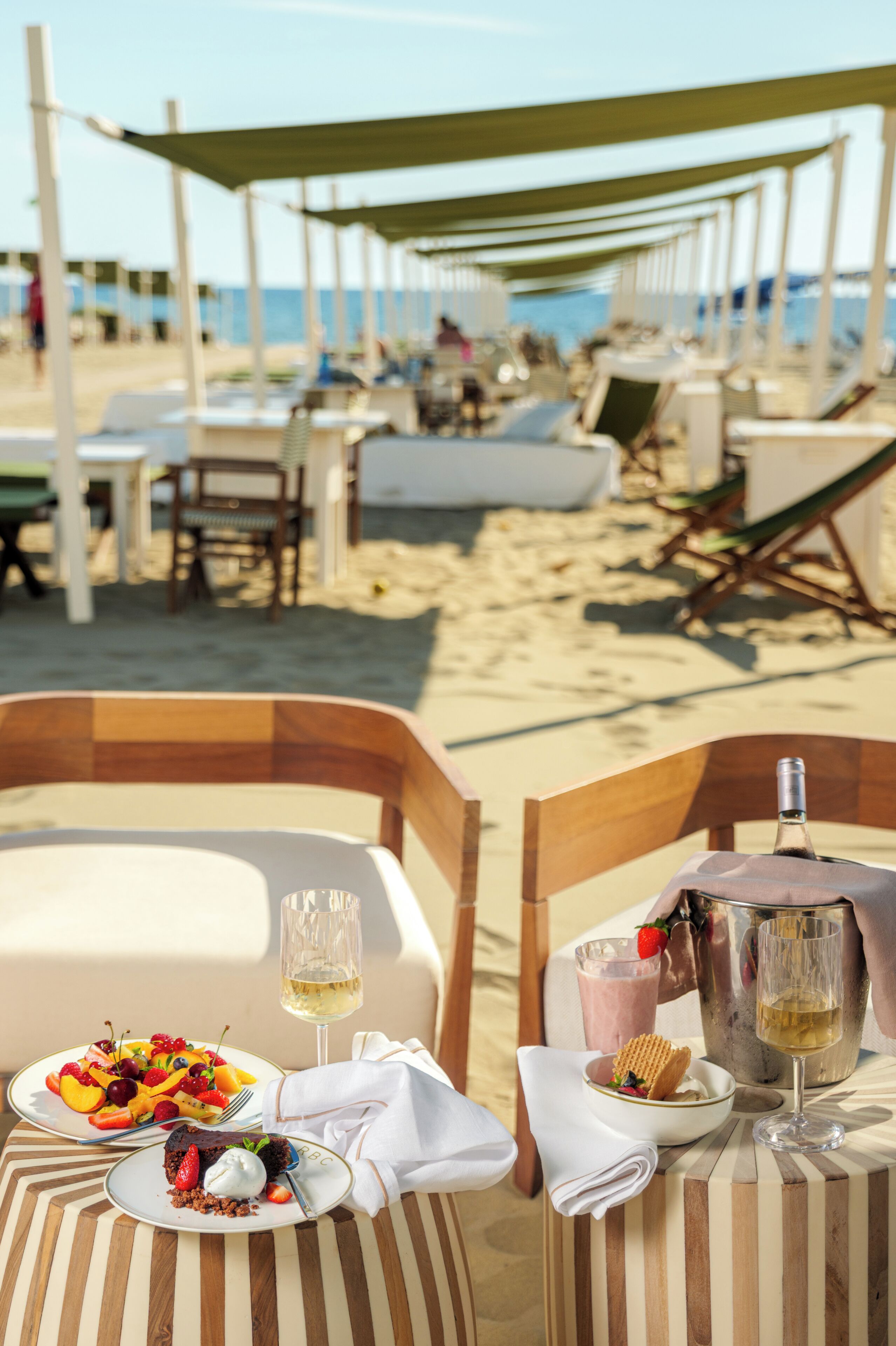 Un'area ristoro in spiaggia, con tavoli, sedie e vista sulla spiaggia e sull'oceano.