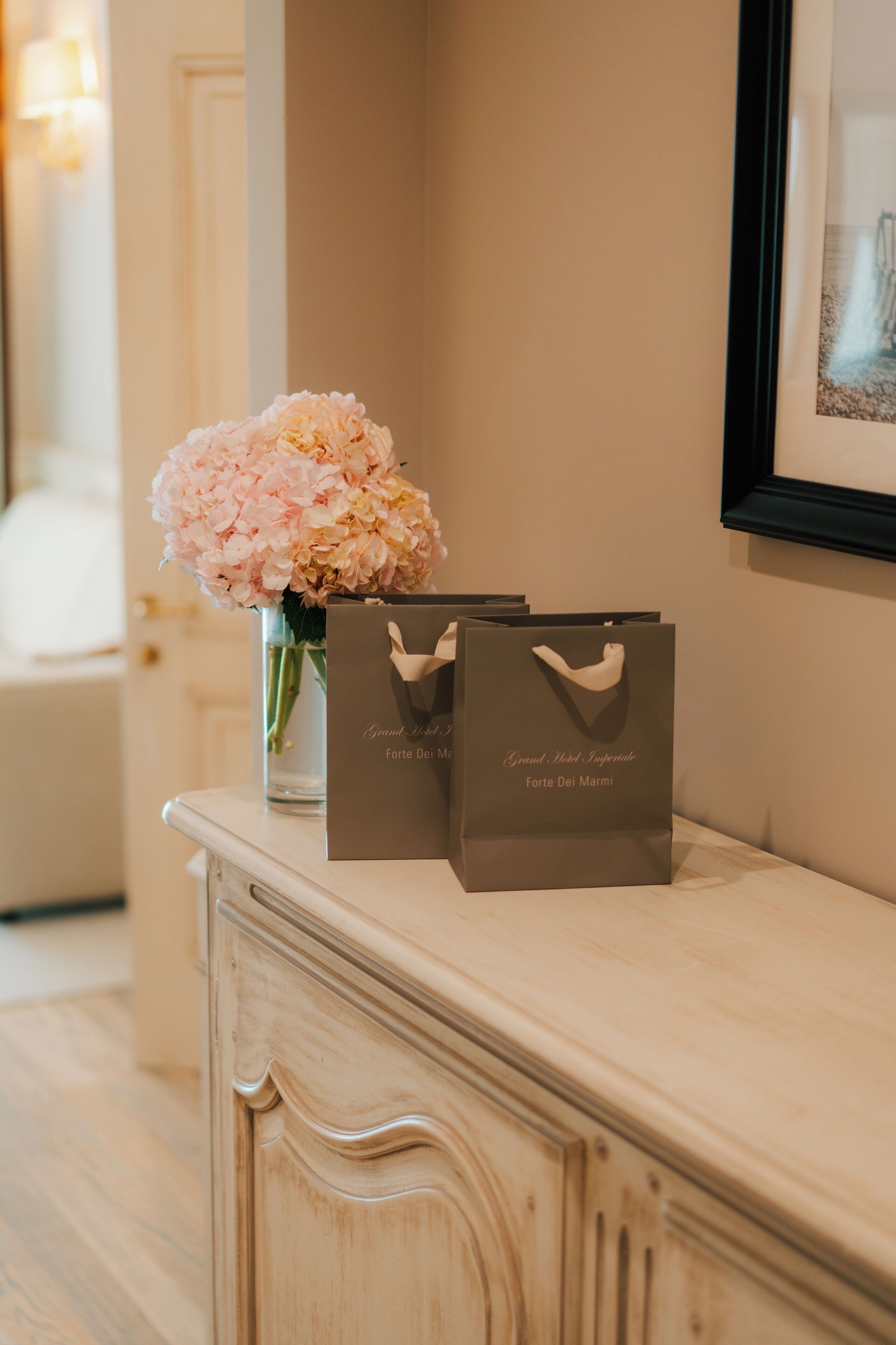 Ein Marmor-Empfangstresen mit zwei braunen Geschenksäcken und einer Vase mit rosa Blumen.