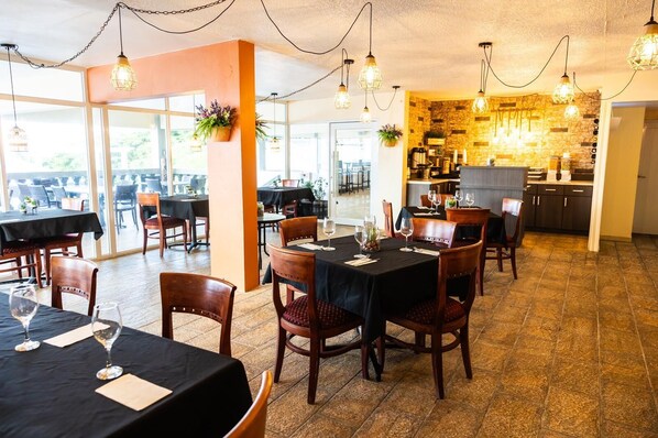 Un restaurante con mesas dispuestas para comer, una zona de cocina y vistas al exterior.