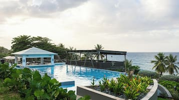 Una piscina al aire libre, sombrillas, sillones reclinables de piscina