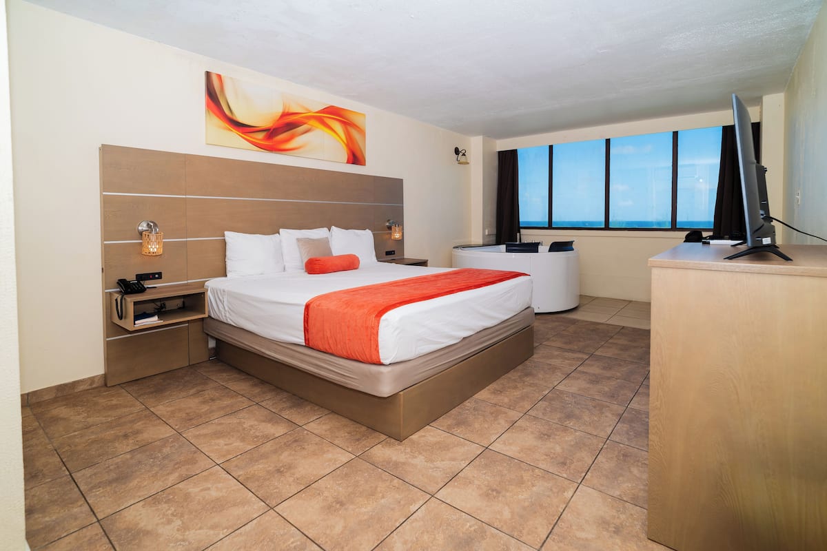 A hotel room with a bed, a desk, a TV, and a large window.