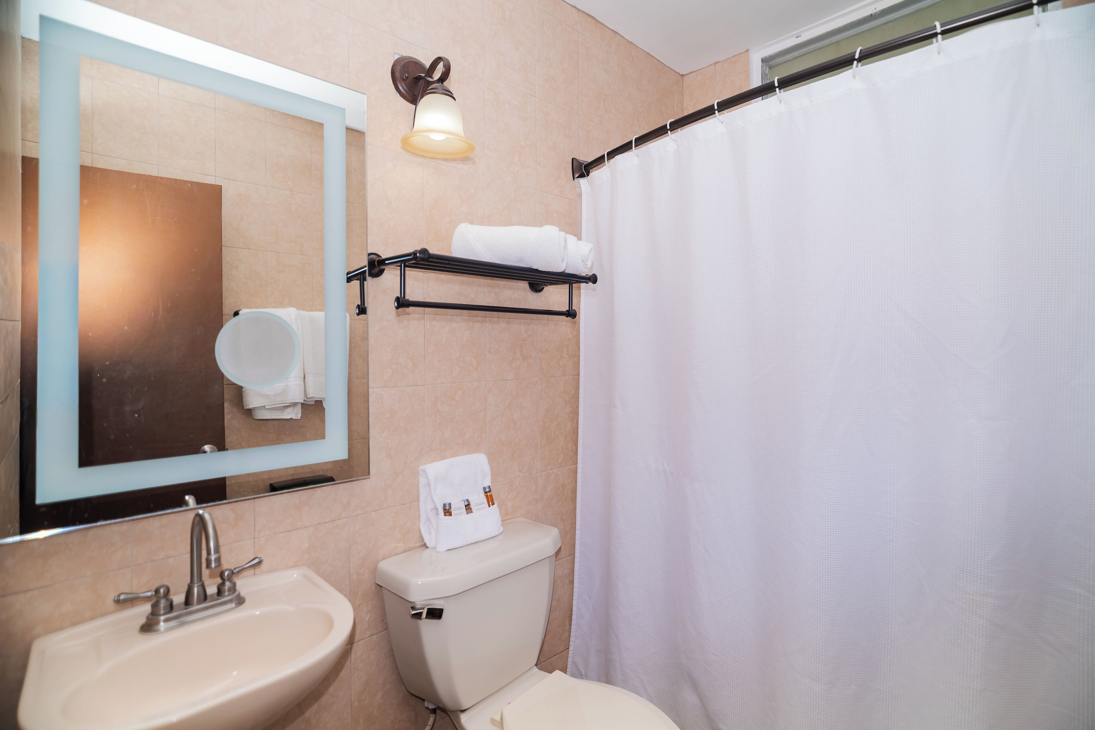 A bathroom with a sink, toilet, and a shower curtain.