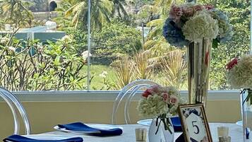 A table set with clear chairs, a floral centerpiece, and a number sign.