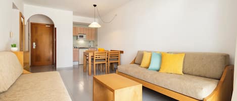 A modern living room with a sofa, coffee table, and dining area.