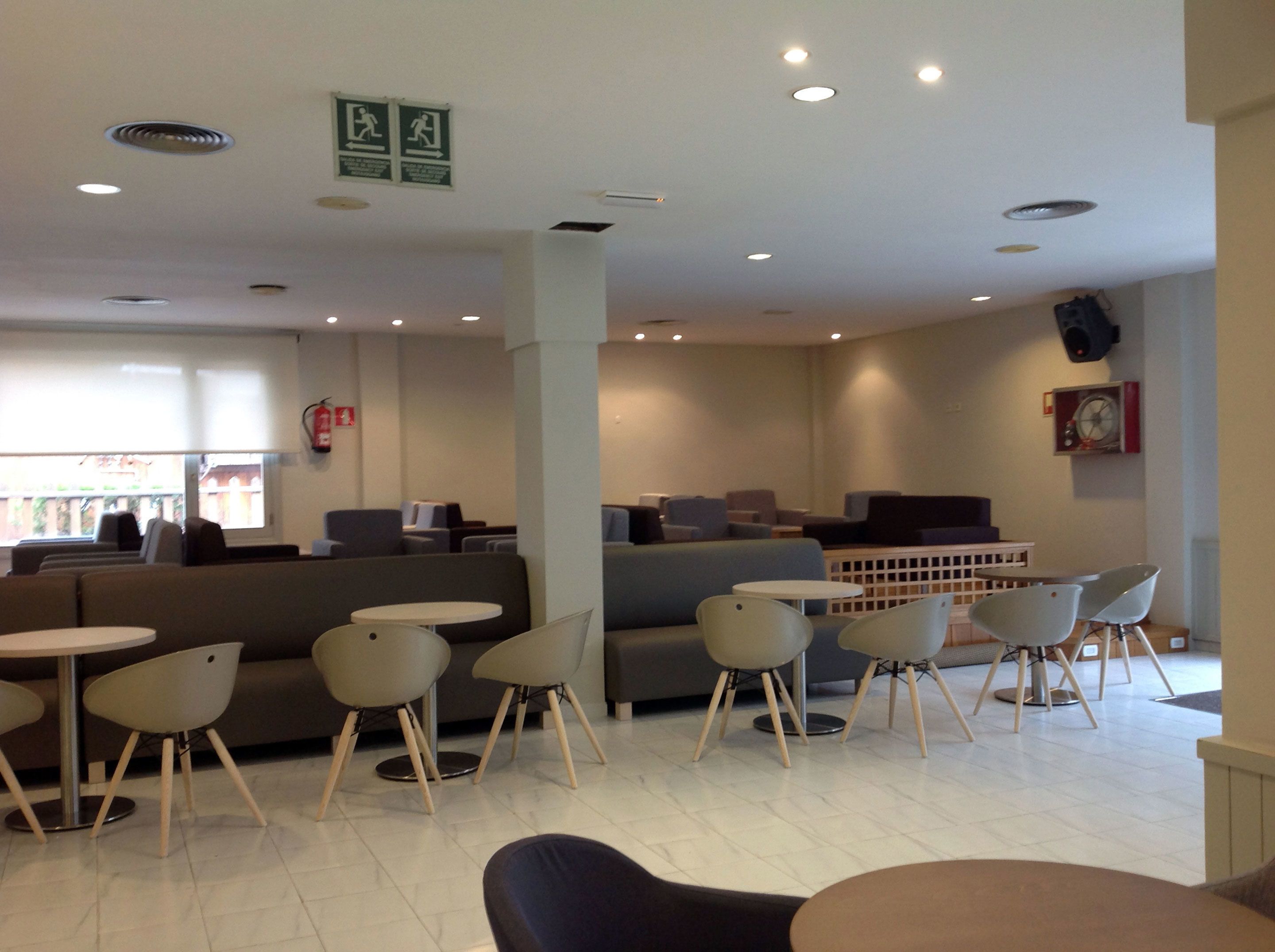 A modern interior with seating areas, tables, and a visible fire extinguisher.