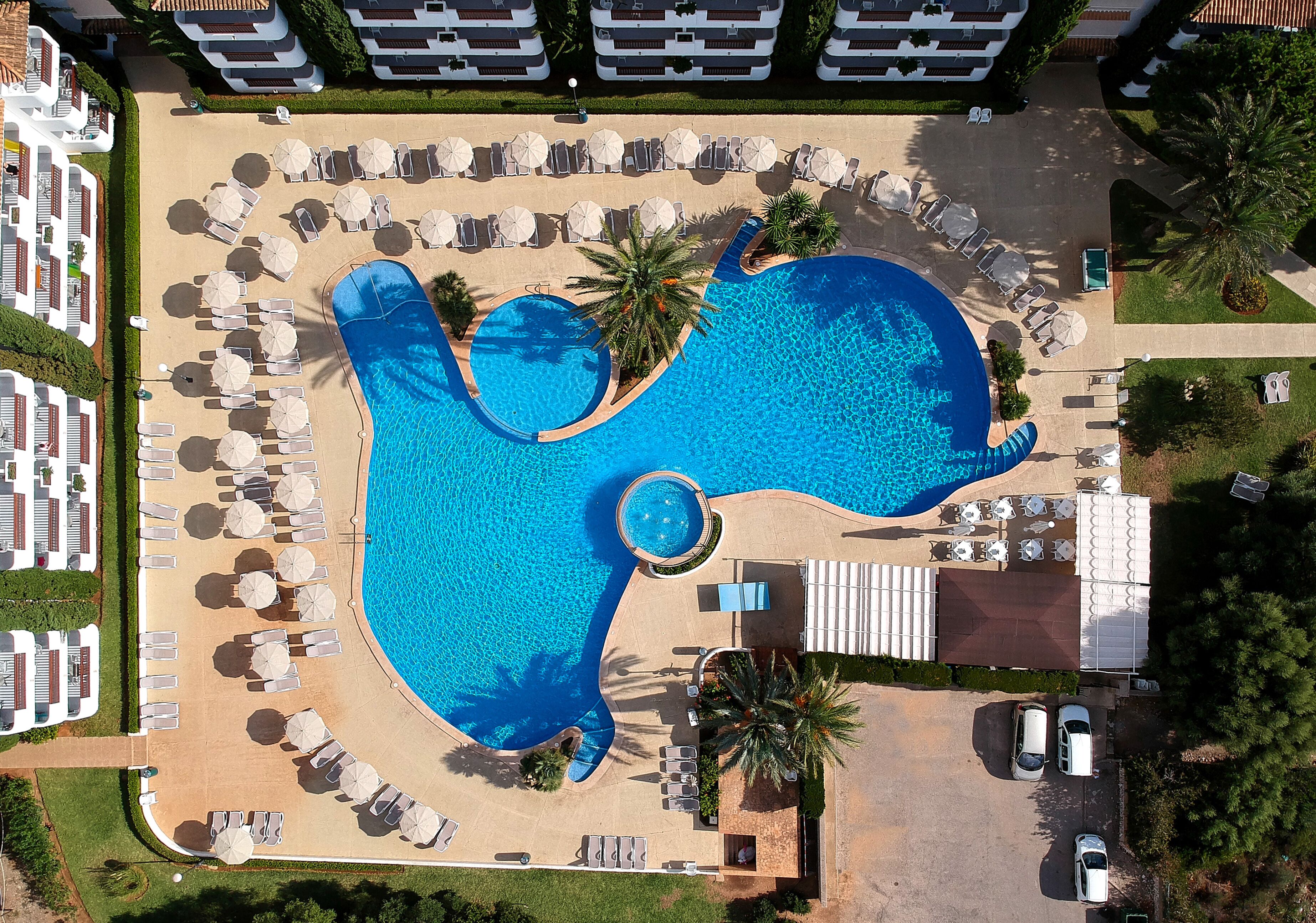 Una piscina al aire libre, sombrillas, tumbonas