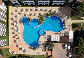Una piscina al aire libre, sombrillas, tumbonas