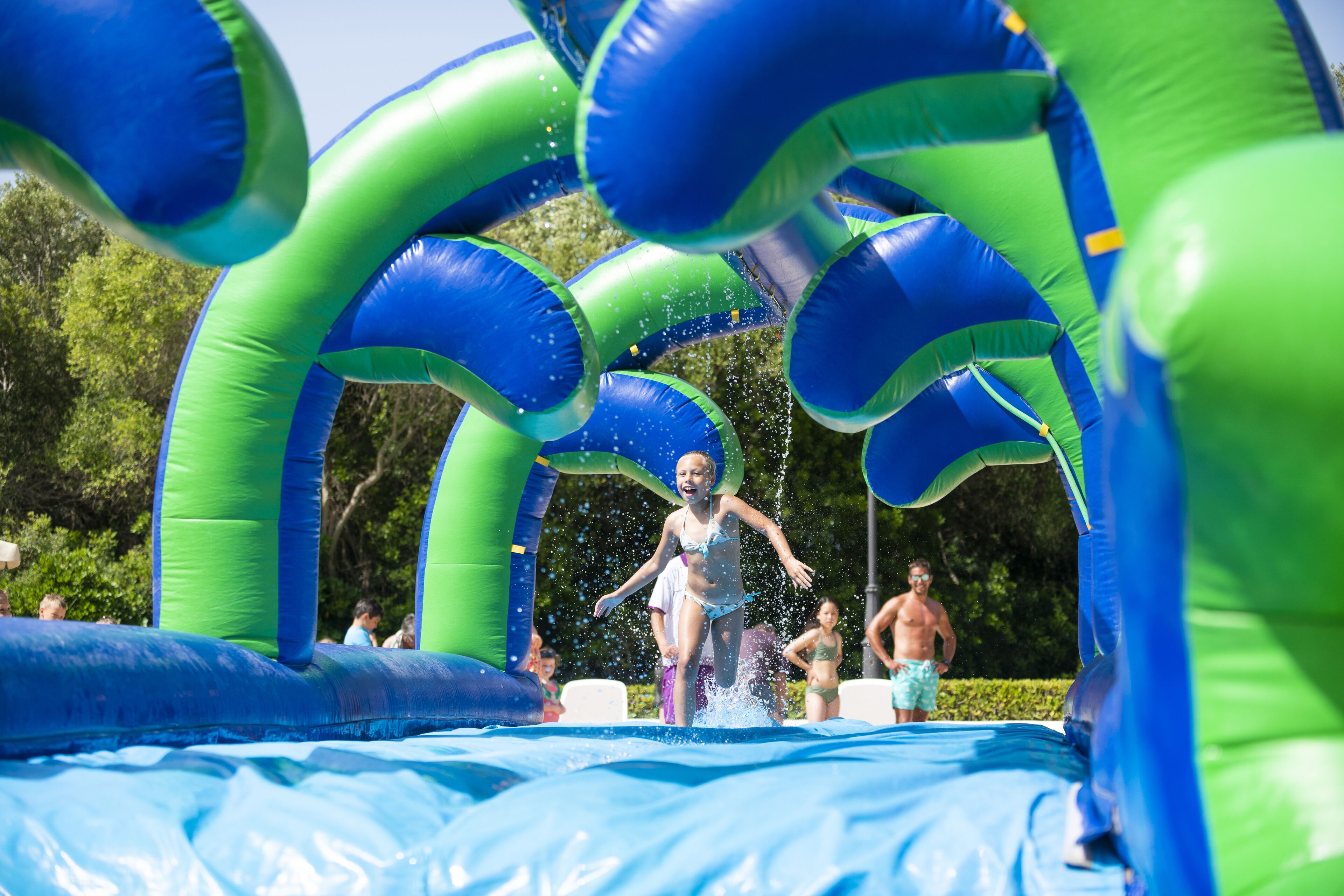 Une aire de jeux aquatique gonflable avec des arches vertes et bleues.
