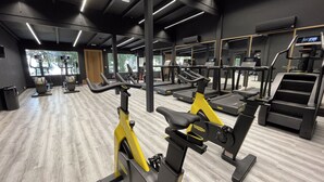 A gym with exercise equipment, including treadmills and stationary bikes, and large windows allowing natural light.
