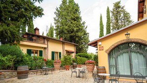 A courtyard with stone flooring, outdoor seating, potted plants, and a building with a balcony. - Agriturismo Vecchio Borgo di Inalbi (Impruneta)