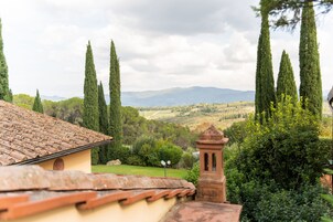 Una villa con techo de tejas, una torre de campanas y vistas al campo.