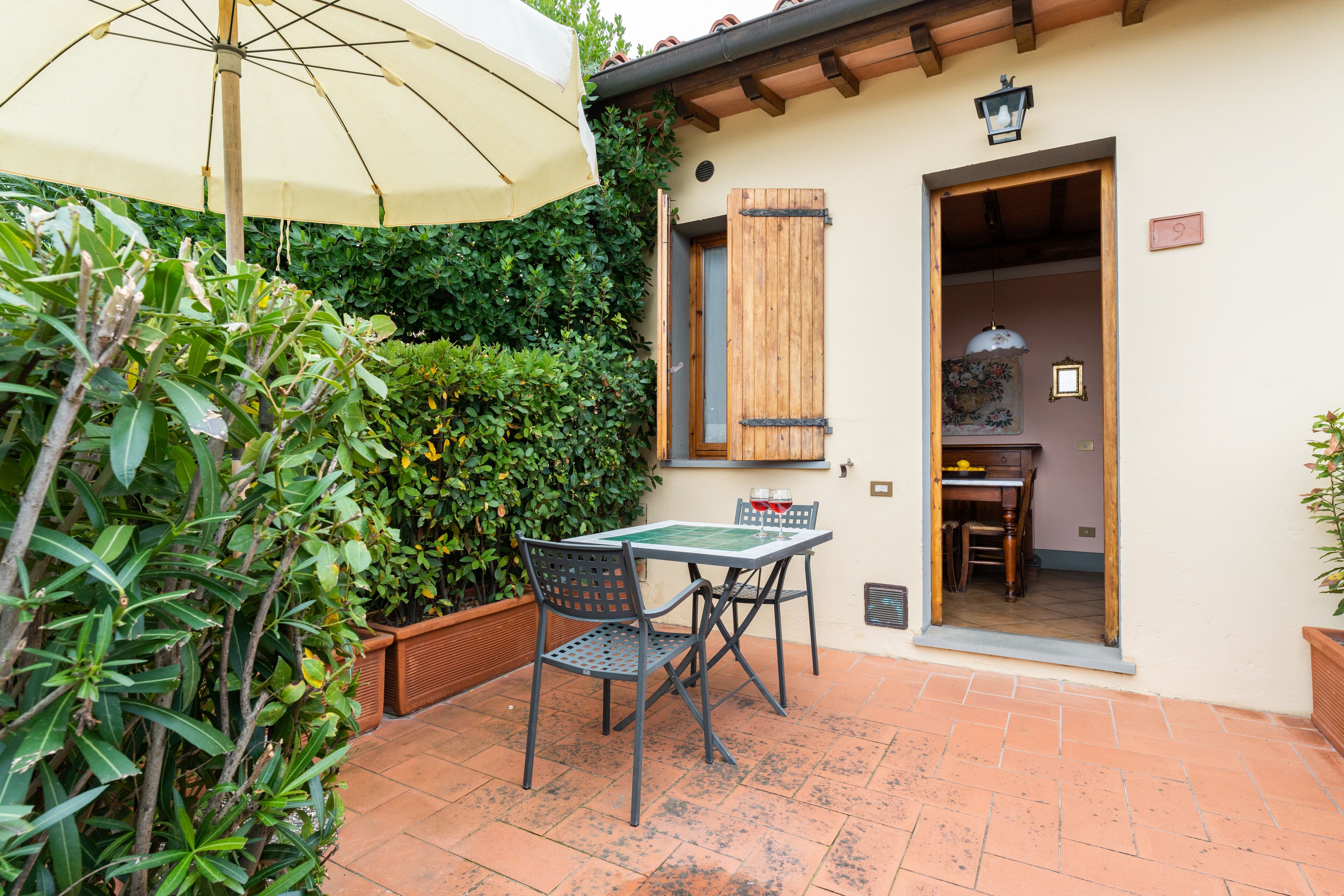 An outdoor patio with a table and chairs, a wooden door, and a window with shutters.