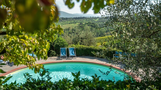 A swimming pool with lounge chairs, surrounded by greenery and hills in the background. - Agriturismo Vecchio Borgo di Inalbi (Impruneta)