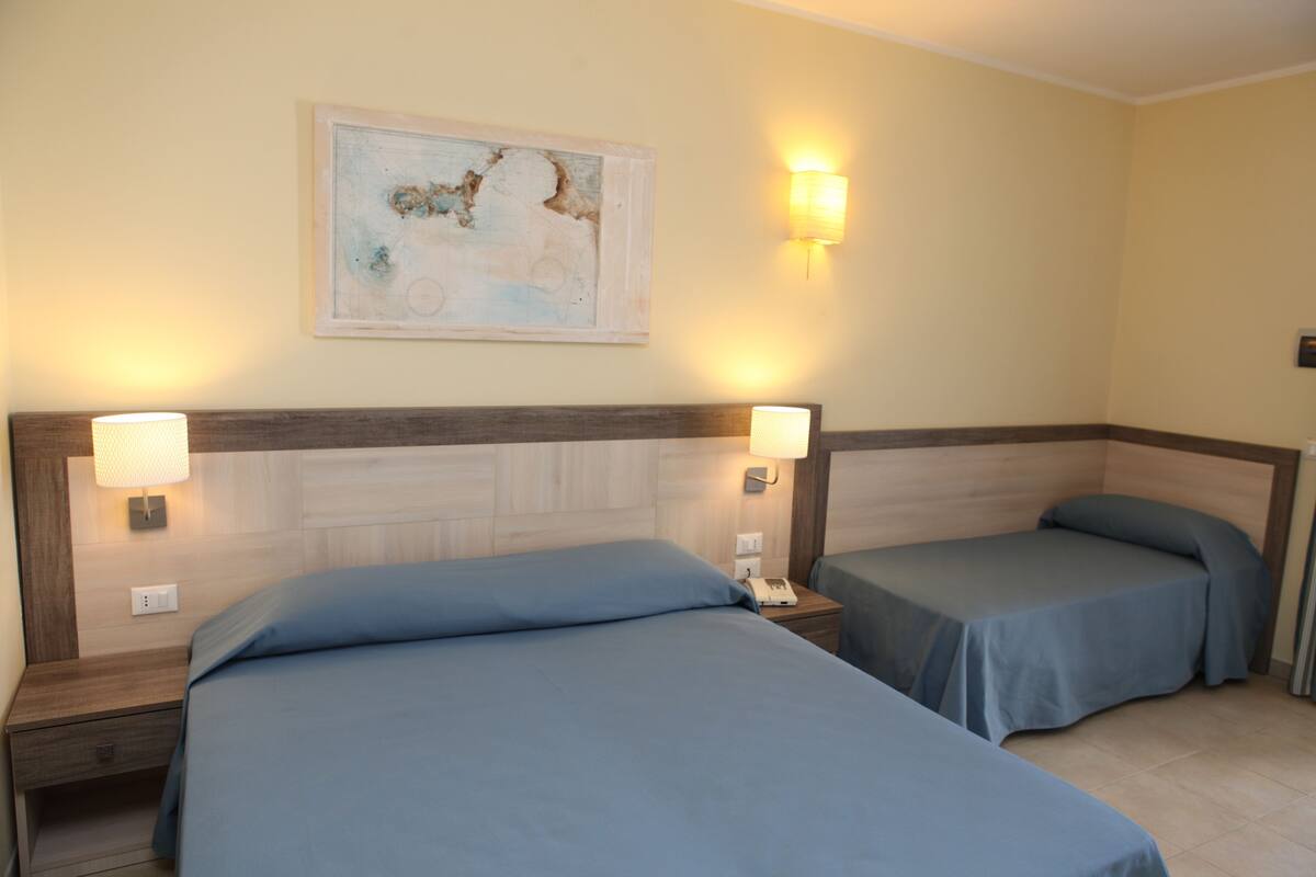 A hotel room with two single beds, each with a bedside lamp and a telephone.