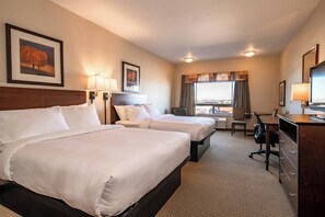 Ein Hotelzimmer mit zwei Betten, einem Schreibtisch, einem Stuhl, einer Kommode und einem Vorhangfenster.
