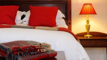A neatly made bed with red and white bedding, a wooden headboard, and a bedside table with a lamp.