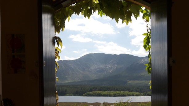 An open doorway leading to a stone pathway with a view of a lake and mountains.