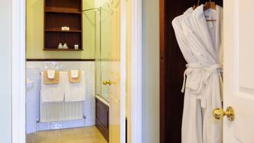 A bathroom with a glass shower, a white radiator, and a wooden shelf with toiletries.