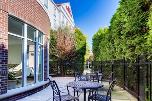 A patio area with outdoor seating and a brick building with large windows. - Hilton Garden Inn Louisville/Northeast (Louisville)