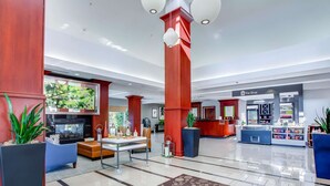 A spacious lobby with a reception desk, a coffee station, and a seating area with a fireplace.