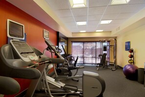 Un gimnasio con cintas de correr, bicicletas estáticas y pelotas de ejercicio.