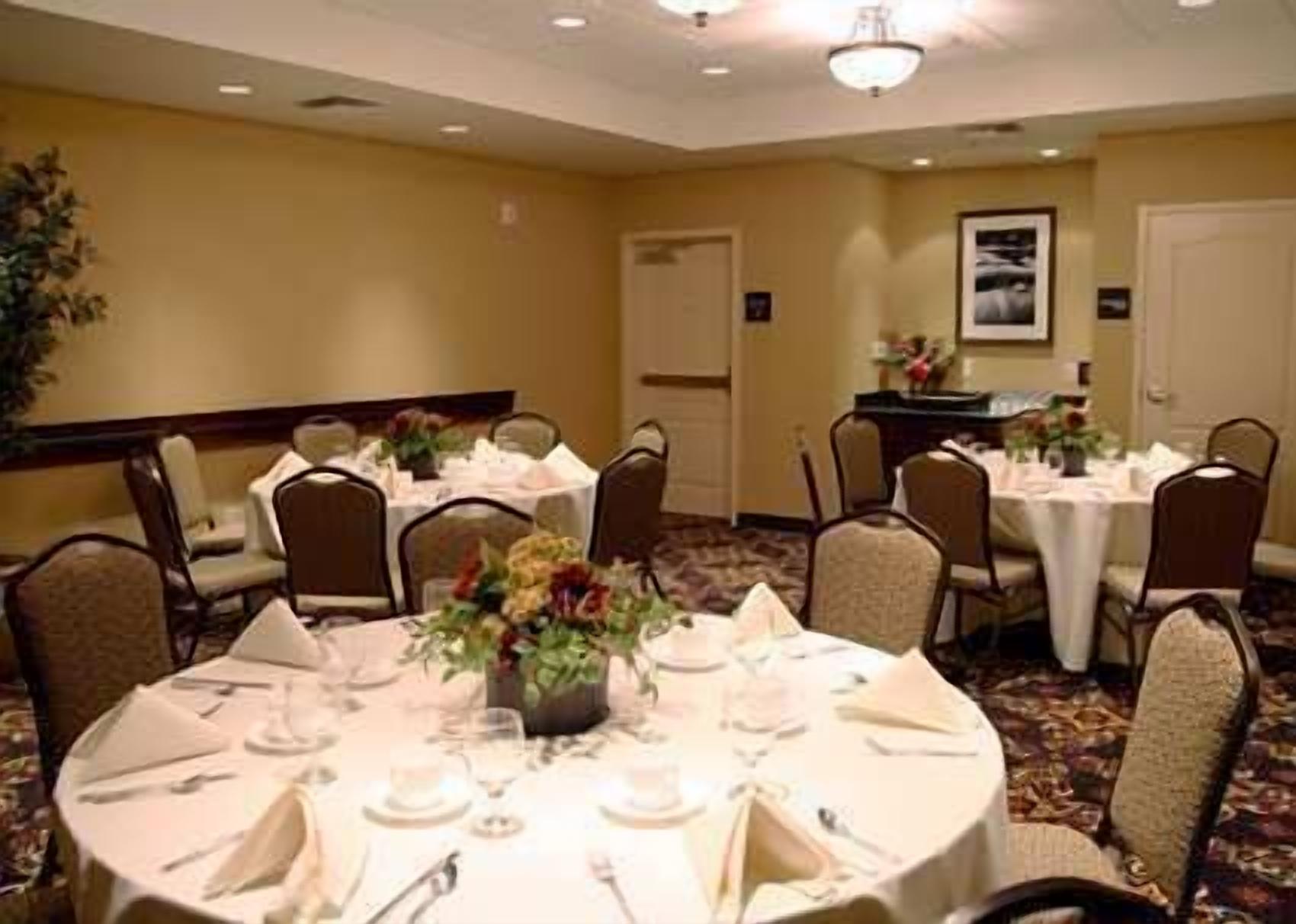 A conference room with round tables, chairs, and floral centerpieces.