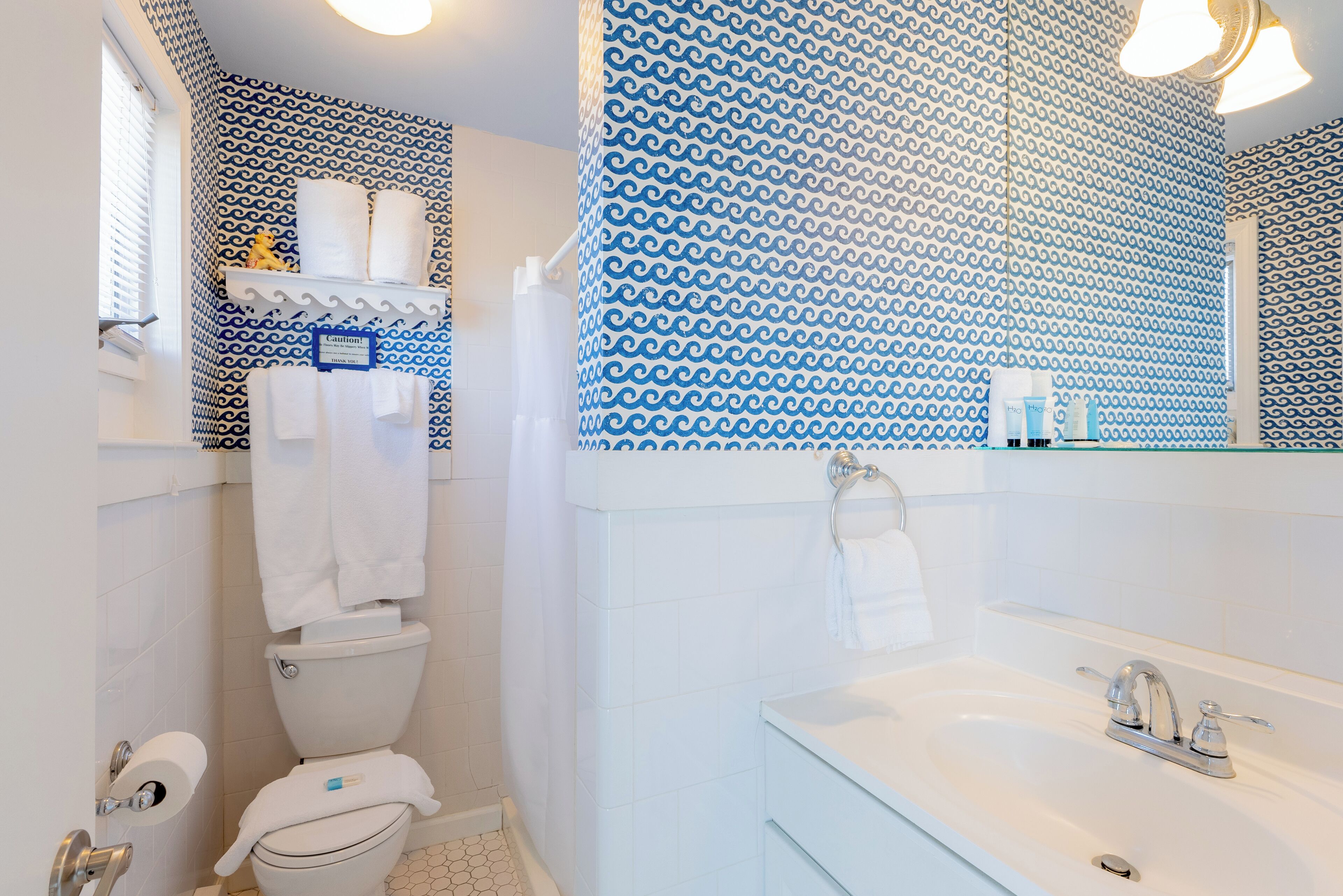 A bathroom with a toilet, sink, and patterned wall.