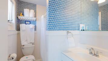 A bathroom with a toilet, sink, and patterned wall.
