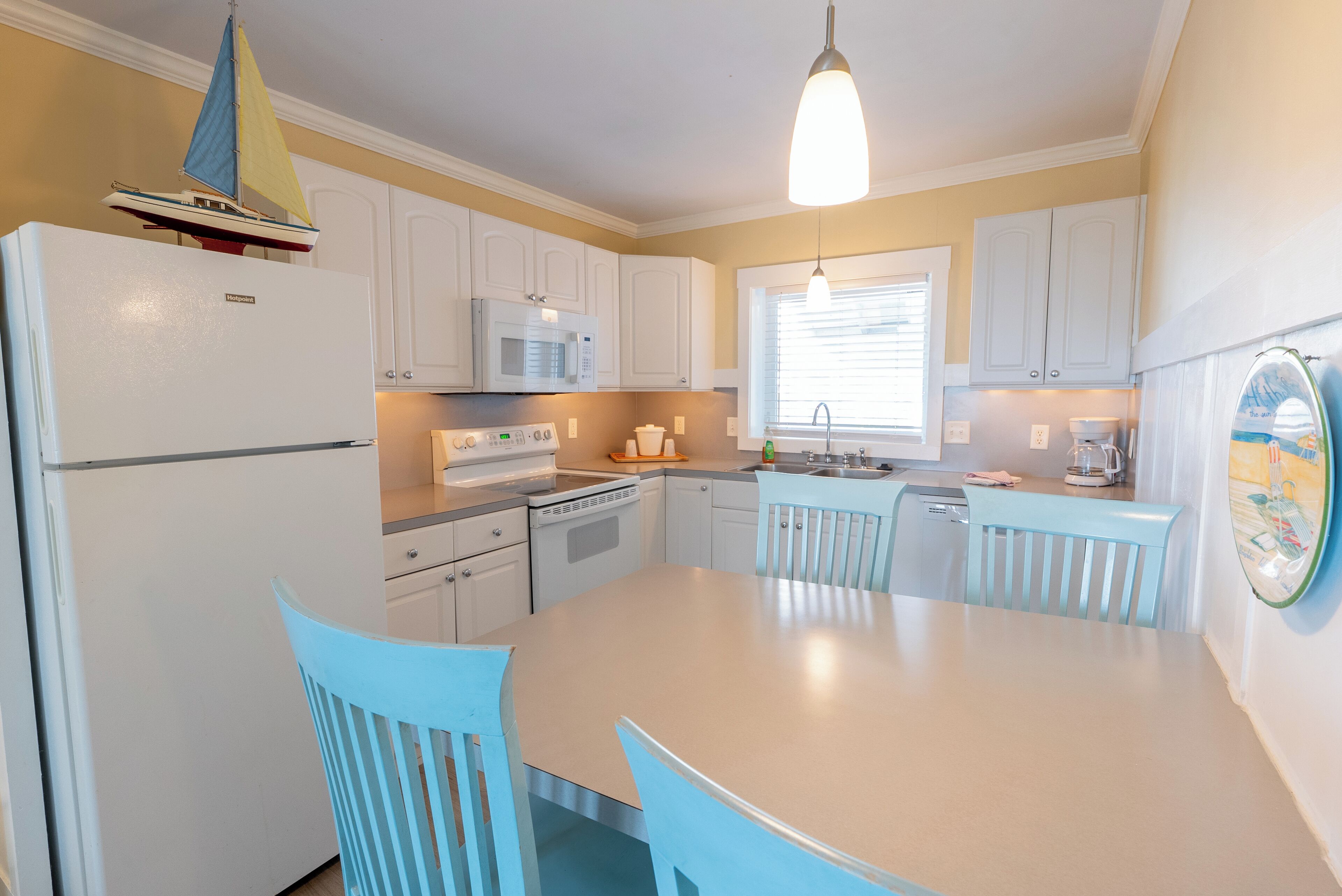 A compact kitchen with white cabinets, a central island, and a hanging light fixture.