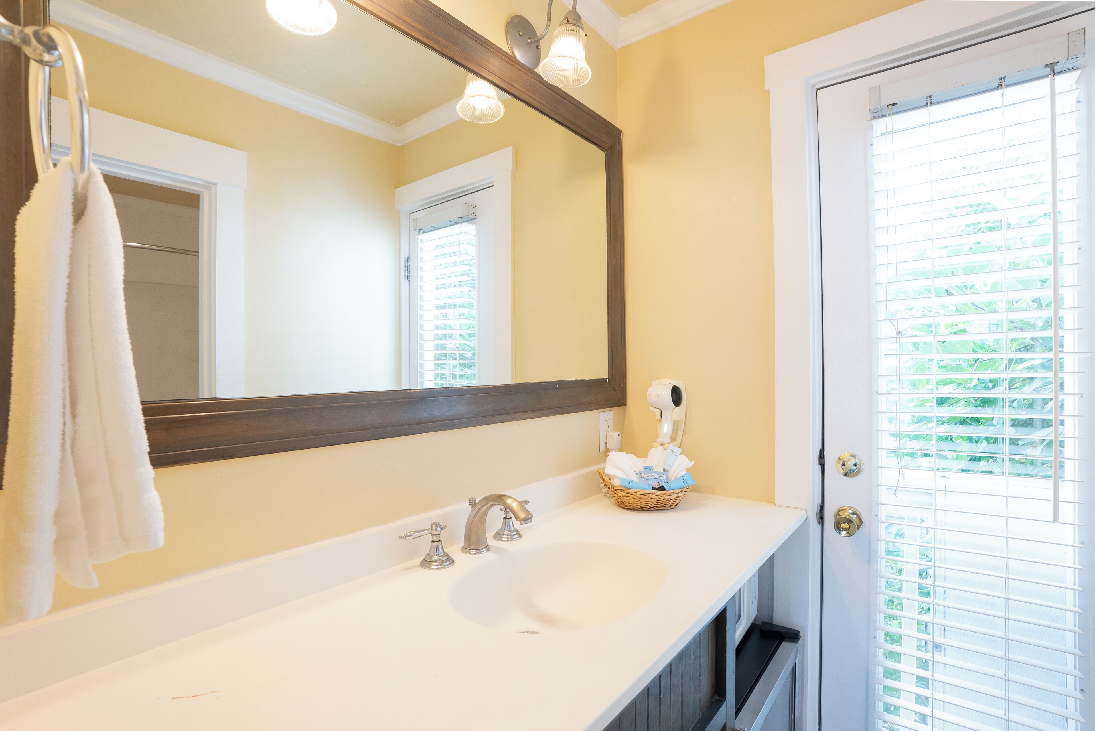 A bathroom with a white sink, a large mirror, and a towel hanging on the wall.