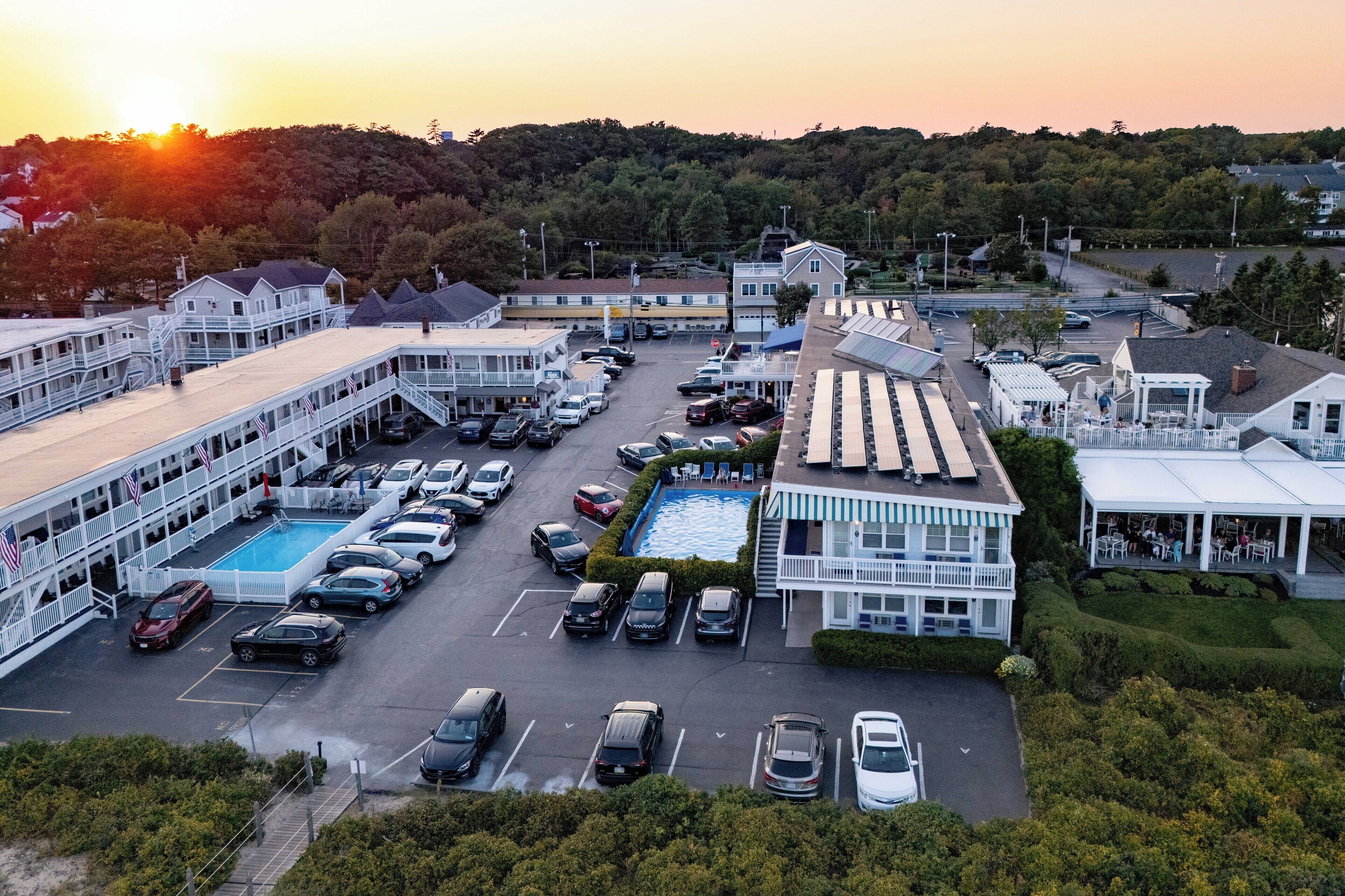 Un hotel con piscina, varios espacios de estacionamiento y vistas a un paisaje montañoso.