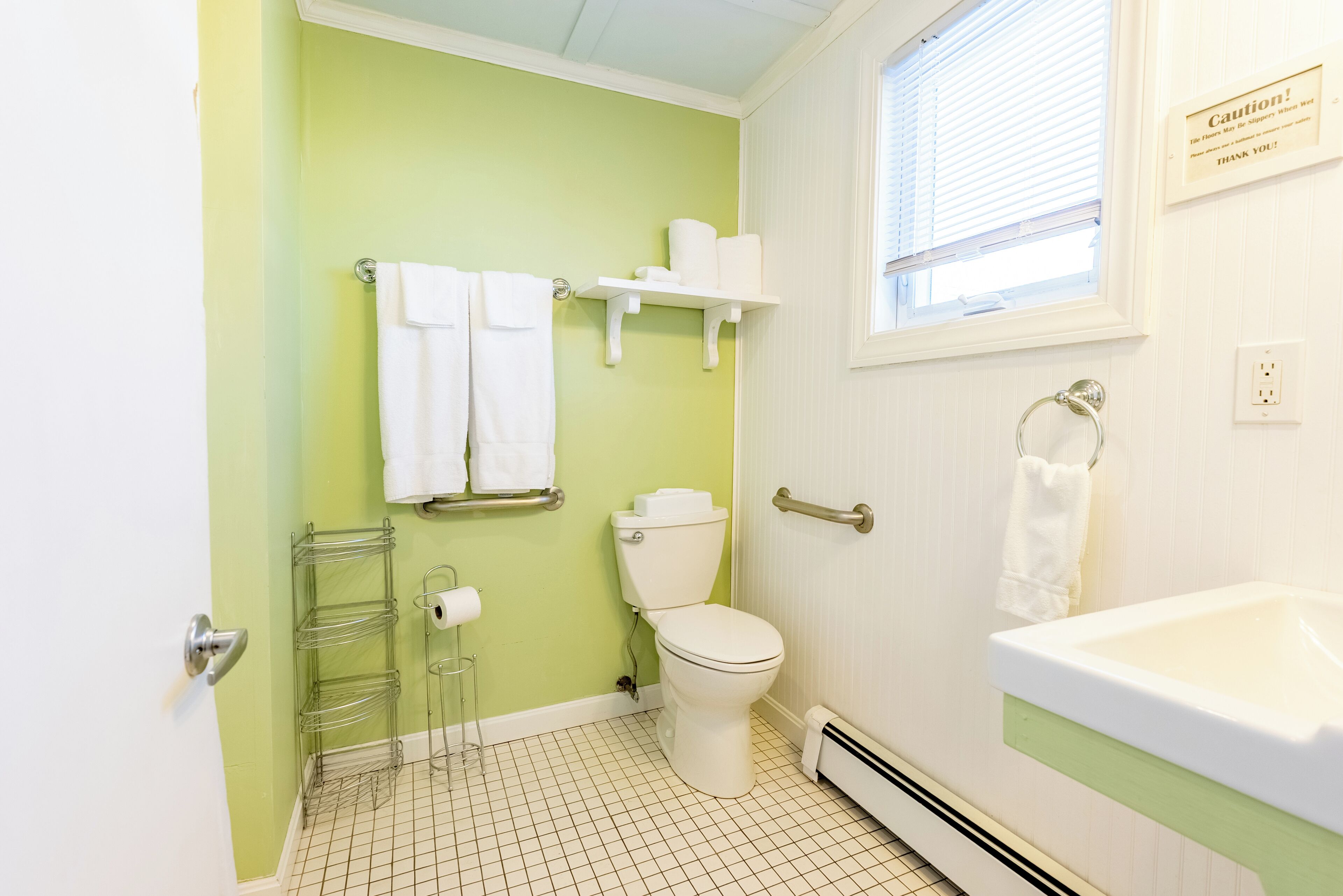 A bathroom with a toilet, sink, and towel rack.