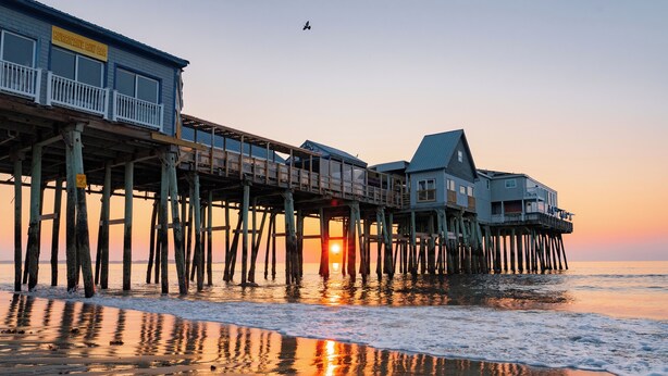A pier with a restaurant named "Hurricane Gulf Bar" and a building with a balcony.