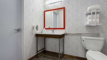A bathroom with a patterned wall, a white toilet, a mirror with a red frame, and a towel rack.