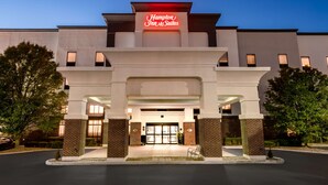 Un hôtel Hampton Inn & Suites doté d’une façade moderne, d’une grande entrée et d’un éclairage extérieur soigné.