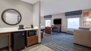 Une chambre d’hôtel équipée d’une kitchenette, d’un bureau, d’un canapé et d’une grande fenêtre.