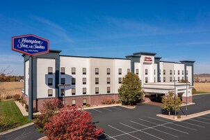 Edificio de un Hampton Inn & Suites by Hilton con estacionamiento y cielo despejado.