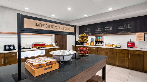 Un espace proposant un buffet pour le petit-déjeuner, avec une pancarte indiquant : « C’EST ICI QUE COMMENCE UN PETIT-DÉJEUNER RÉUSSI. »