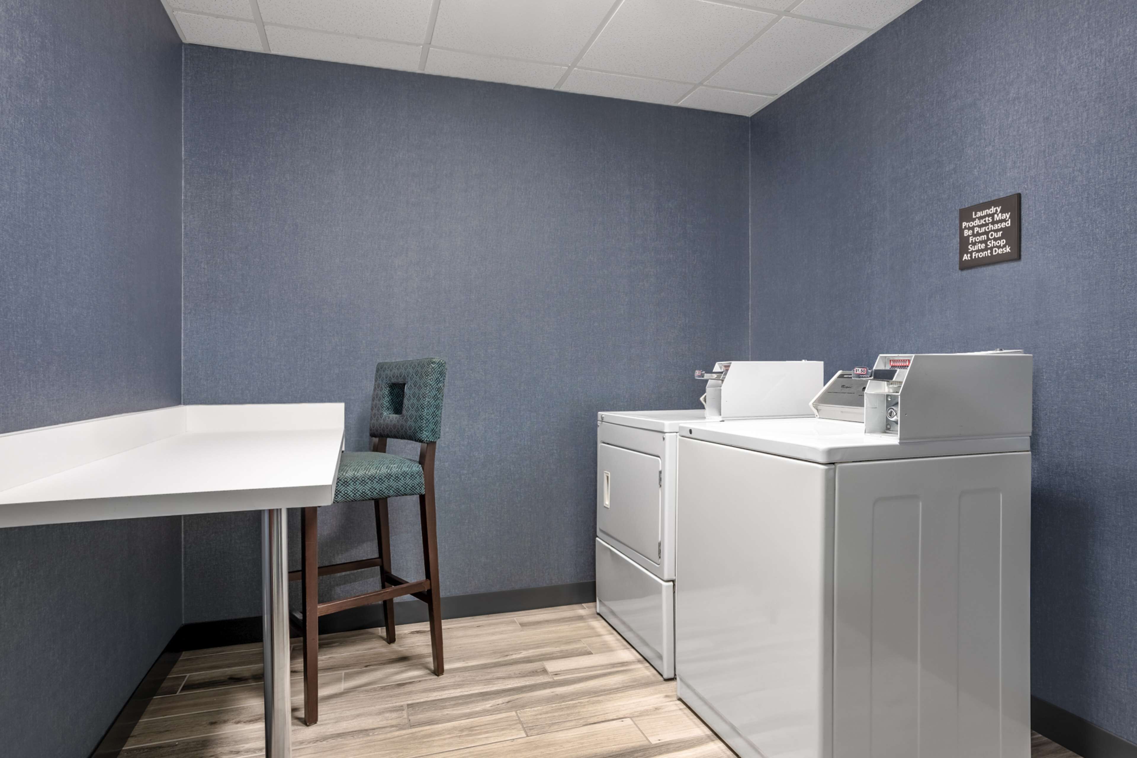 A laundry room with a washing machine, a chair, and a table.
