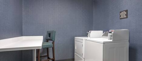 A laundry room with a washing machine, a chair, and a table.