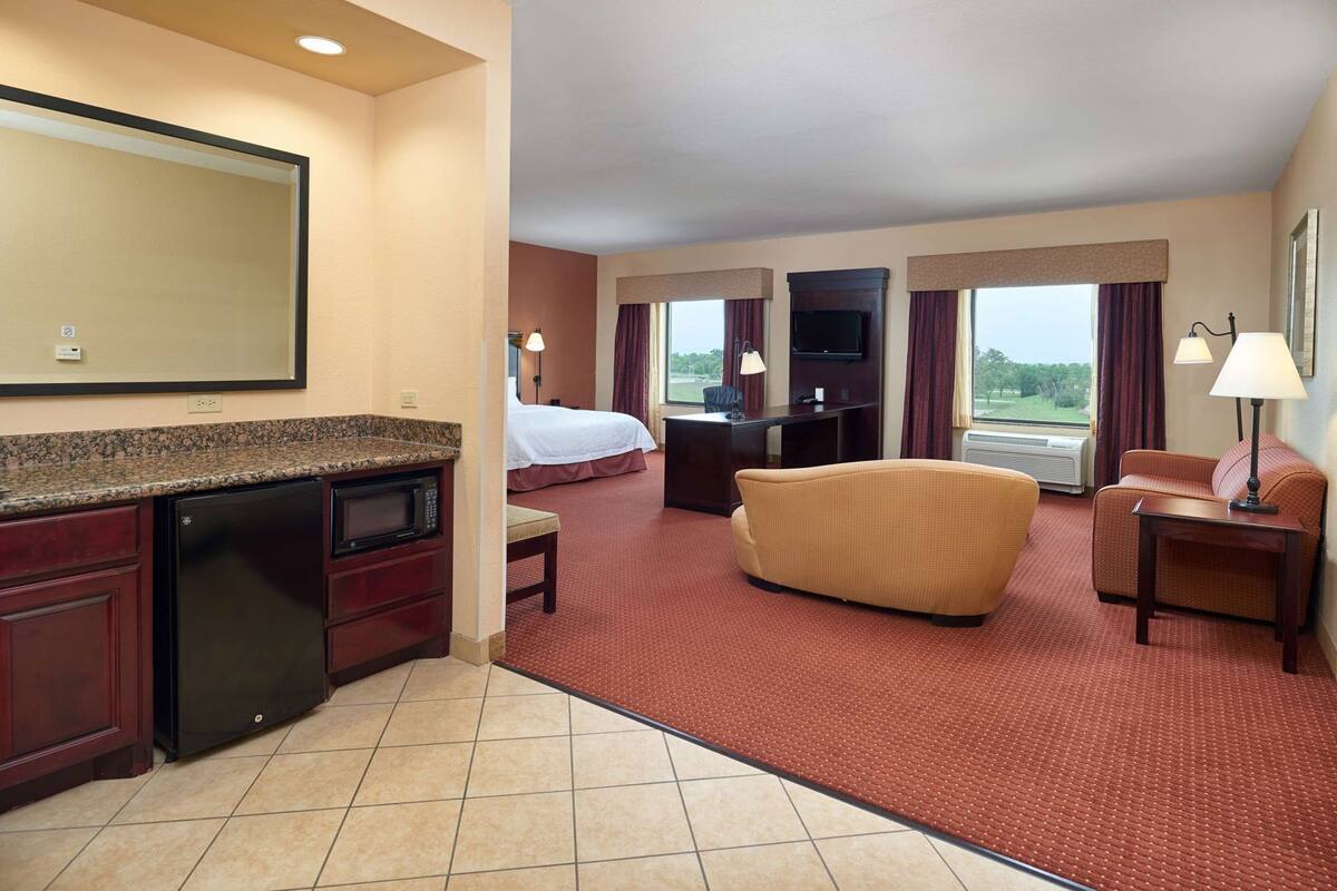 Une chambre d’hôtel équipée d’une kitchenette, d’un lit, d’un canapé, d’un bureau et d’une télévision.