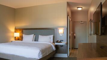 A hotel room with a large bed, bedside lamps, a desk with a phone, and a mirror.