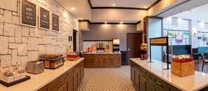 A breakfast area with a stone wall, a coffee machine, and a sign that says 'HAPPY BREAKFAST STARTS HERE.'
