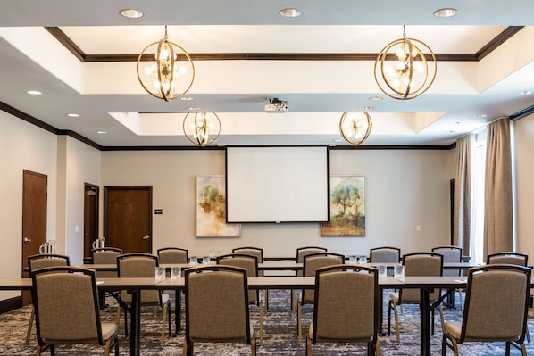 A conference room with a long table, multiple chairs, and a projector screen.