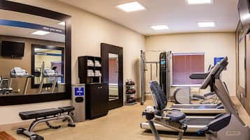 A gym with exercise equipment, a bench, a mirror, and a wall-mounted TV.